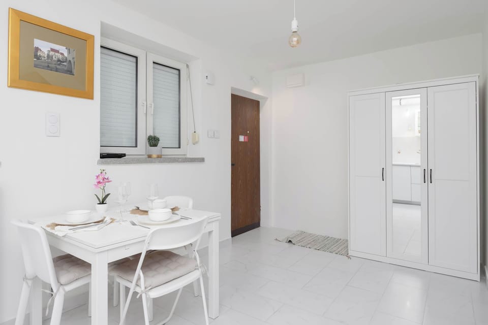 Another view of the kitchen with the dining area and white cabinetry. The layout allows for easy cooking and dining.