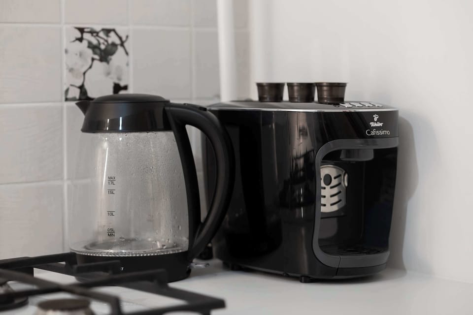 A coffee station setup with a kettle and coffee machine in the kitchen. The area is neatly arranged for convenience.