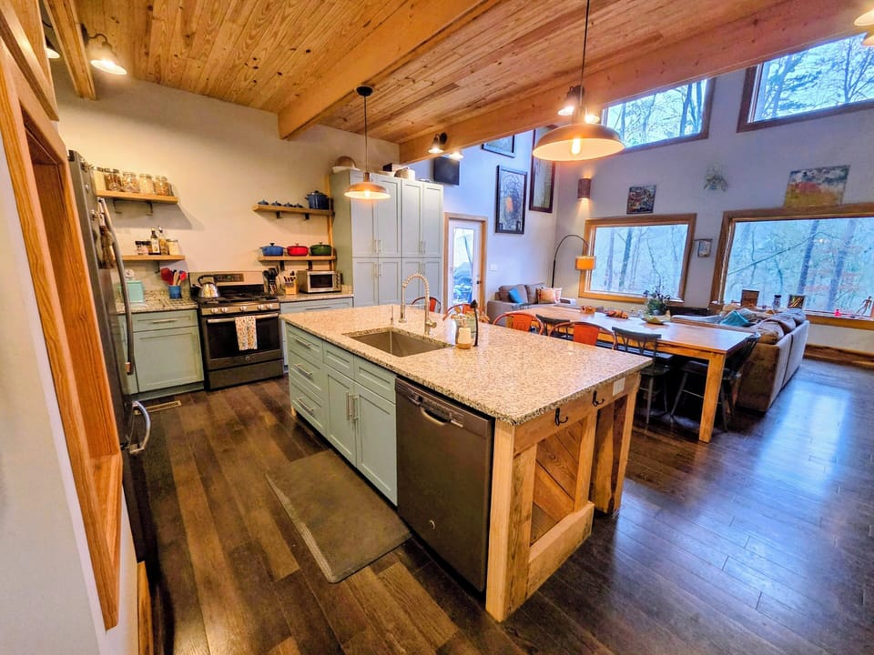 The open kitchen feeds into the great room with stunning forest and river views