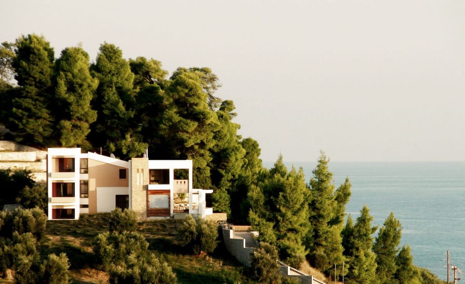 View of the villa nestled among pine trees, overlooking the sea