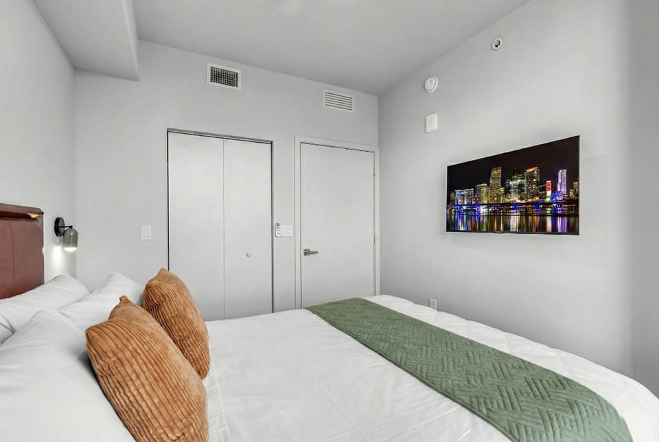 Cozy queen bedroom featuring fresh linens and a wall-mounted TV.