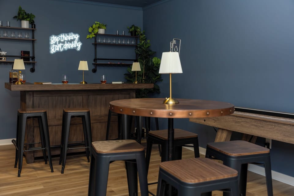 Host your own speakeasy night in this stylish basement bar, complete with high-top seating, a neon glow, and a shuffleboard table for added fun.
