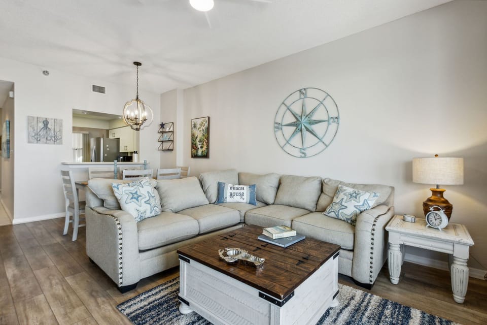 ​Cozy living area features a plush sectional sofa, coastal accents, and an open layout perfect for relaxing after a day at the beach.