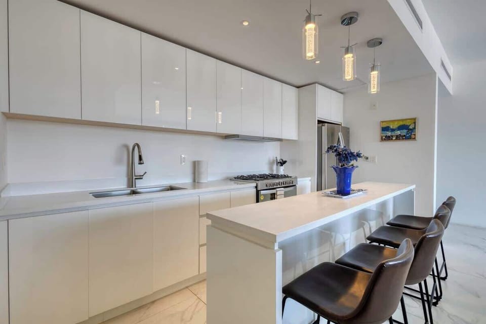 Fully equipped kitchen including blender, toaster, oven, refrigerator, many cooking tools, baking dishes, drinking glasses, and bar ware.