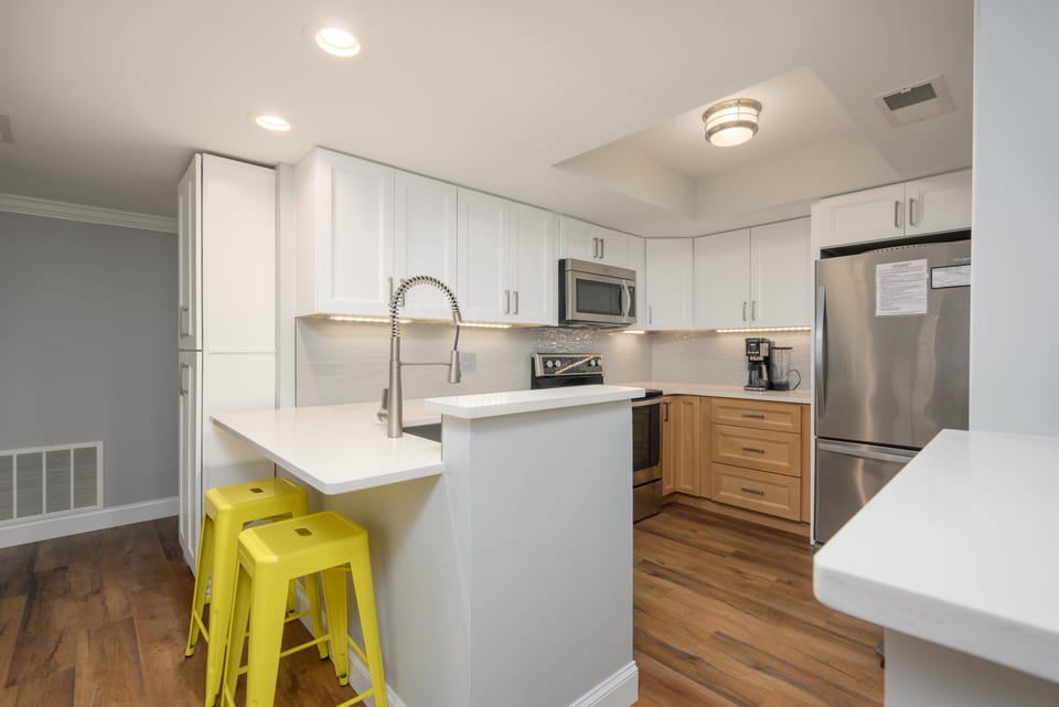 Fully stocked kitchen with stainless steel appliances and 2 barstools for extra seating.