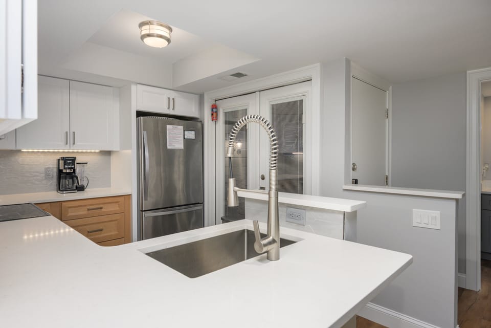 Fully stocked kitchen with stainless steel appliances and 2 barstools for extra seating.