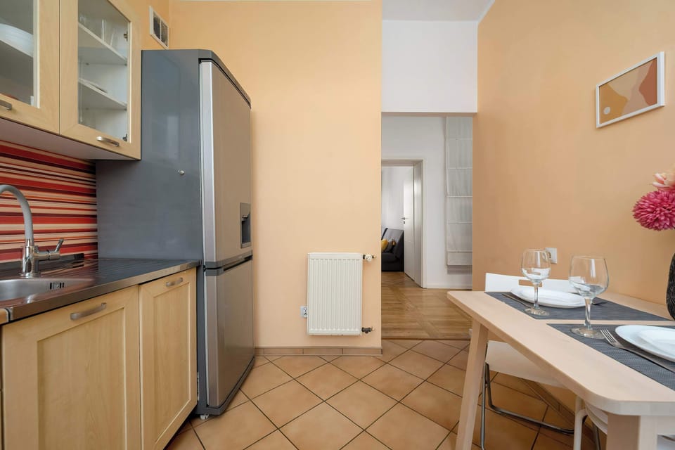 Another angle of the kitchen showing a refrigerator and countertop workspace. The layout appears compact but efficient. Warm colors make the kitchen feel inviting.