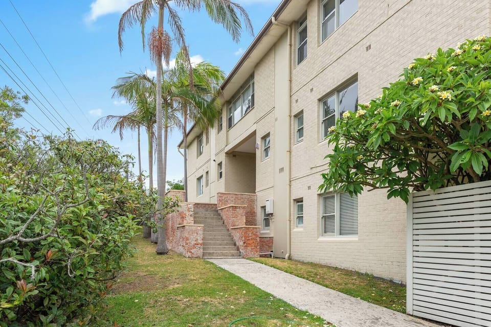 Well-kept exterior leads to shared green spaces, outdoor shower, communal backyard, paid laundry facilities and convenient driveway parking for an easy lifestyle.