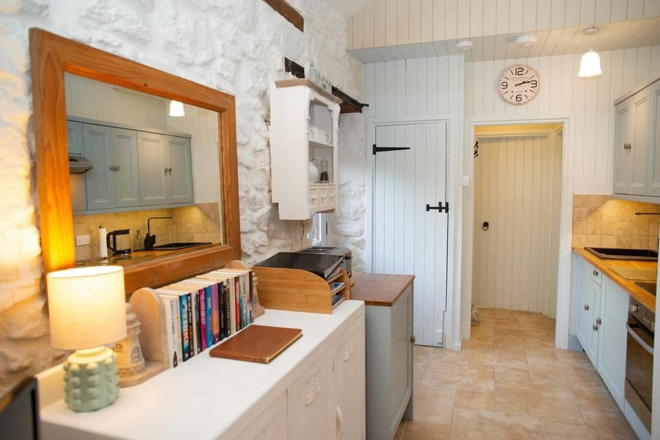 Kitchen view showing sink, countertops, open shelves, and a wall clock