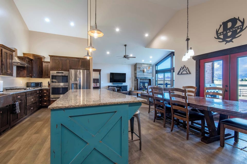 Full kitchen-to-dining perspective — the teal island anchors an open, professionally designed space for meals and conversation.