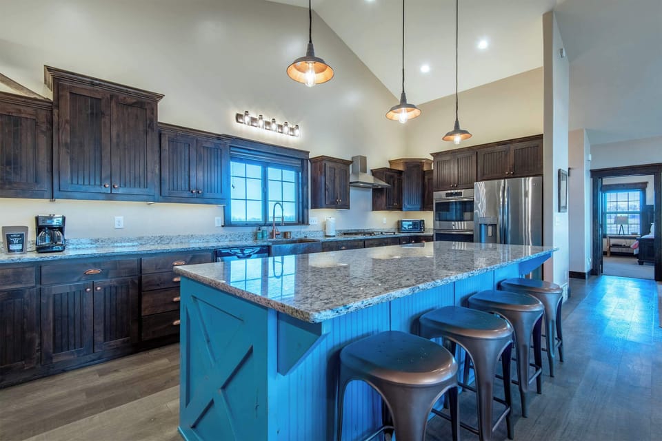 The showstopping teal island with granite counters and bar seating — the heart of the main floor and natural gathering spot.