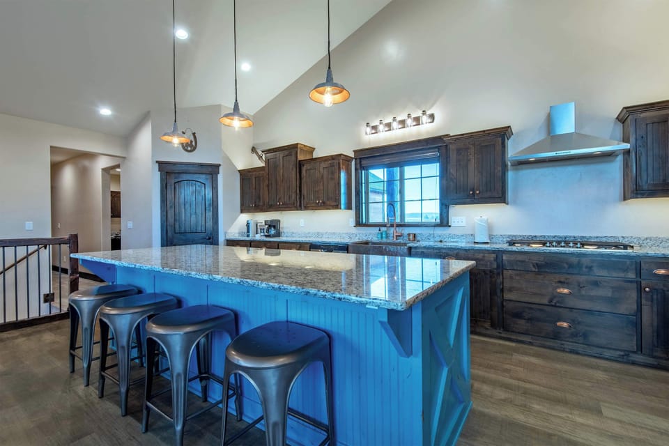 Gourmet kitchen from another angle — dark wood cabinetry, granite counters, and pendant lighting over the showpiece island.