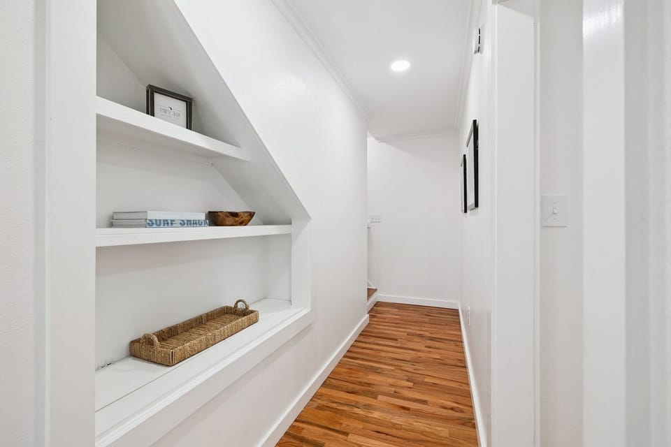 Discover smart storage under the stairs with built-in shelves for your belongings in this bright, organized hallway.