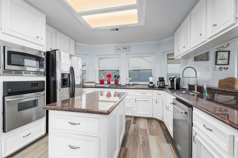 Fully equipped kitchen featuring stainless steel appliances, spacious countertops, white cabinetry, and open layout designed for family meals and entertaining.