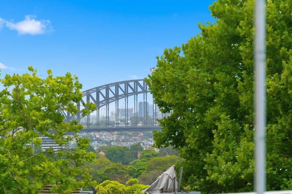 Elevated sightlines reveal leafy surrounds with clear glimpses toward the Sydney Harbour Bridge, especially memorable during major city celebrations.
