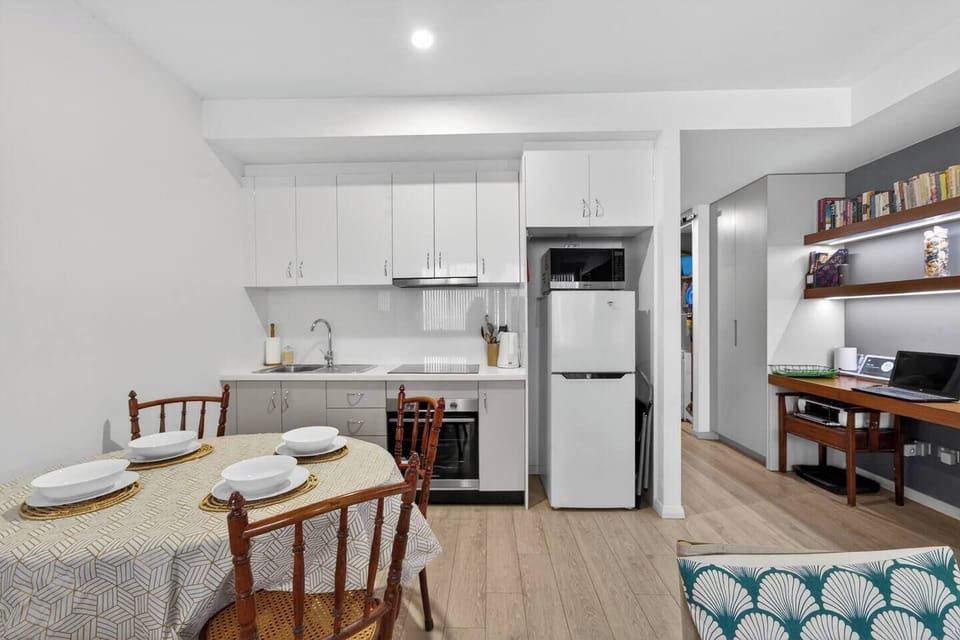 A streamlined kitchen supports home cooking with a cooktop, oven, microwave, dishwasher, fridge, kettle, and toaster, ready for simple, stress-free meals.
