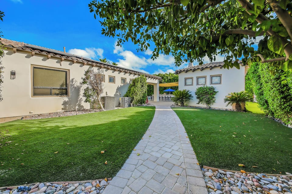 Beautiful landscaped courtyard with lush lawns, a charming walkway, and tropical greenery.