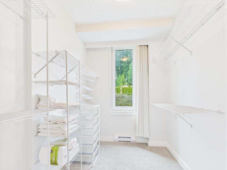 Walk-in closet storage perspective highlighting built-in shelving towers and natural light from the high window.