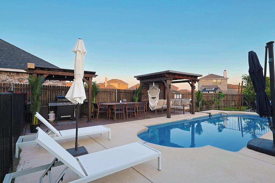 Resort-style backyard with a sparkling pool, shaded lounge cabanas, and plenty of space to relax and entertain.