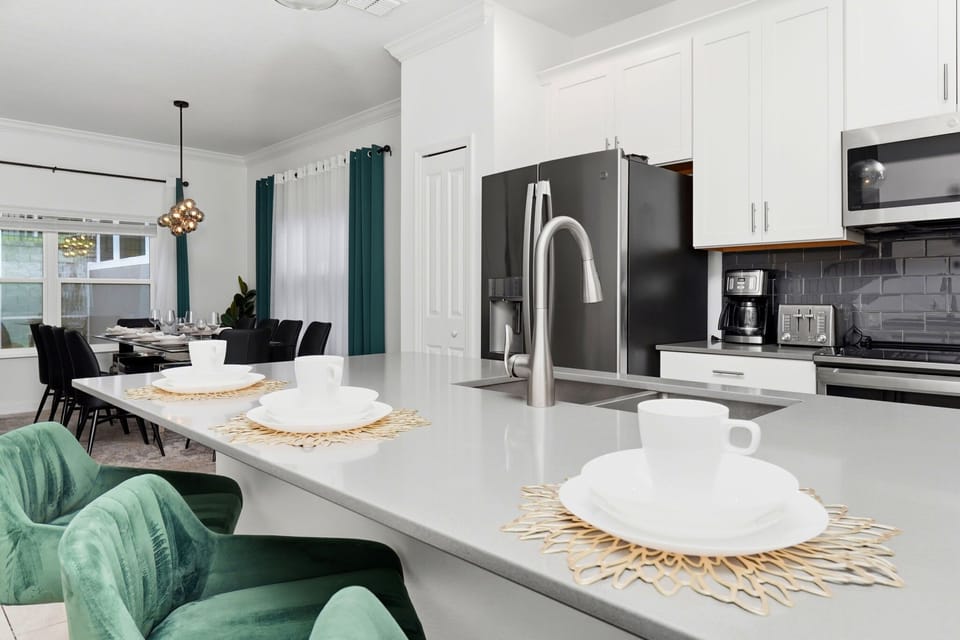 Modern kitchen with a large island and green velvet bar stools for casual dining.