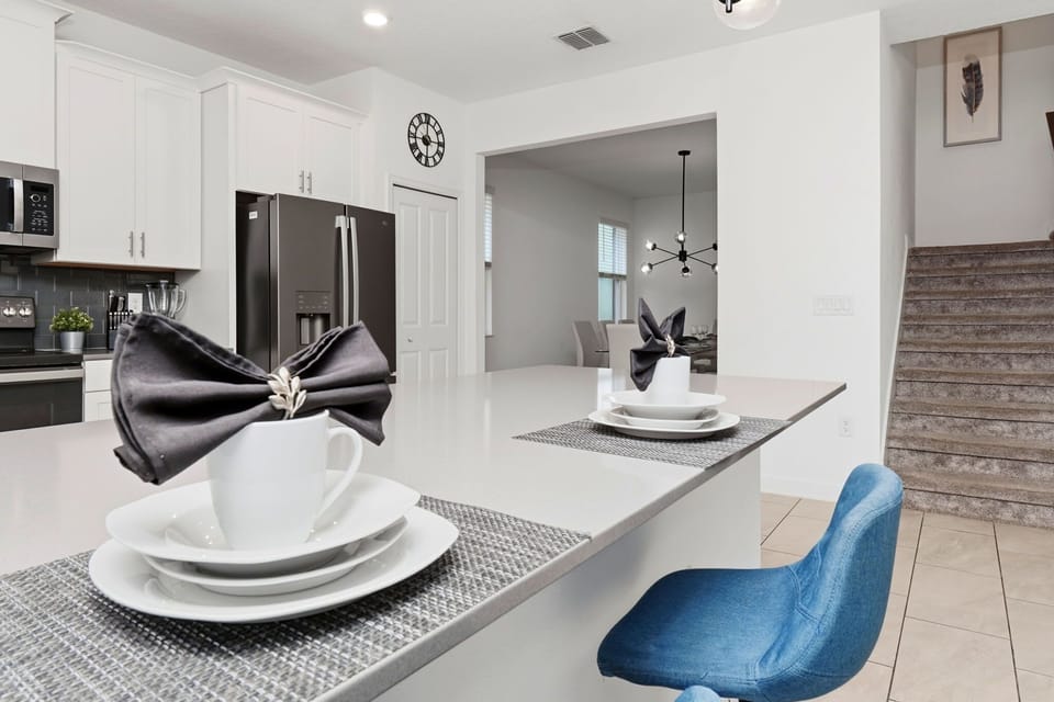 Modern kitchen island with blue seating and a view into the dining area and staircase