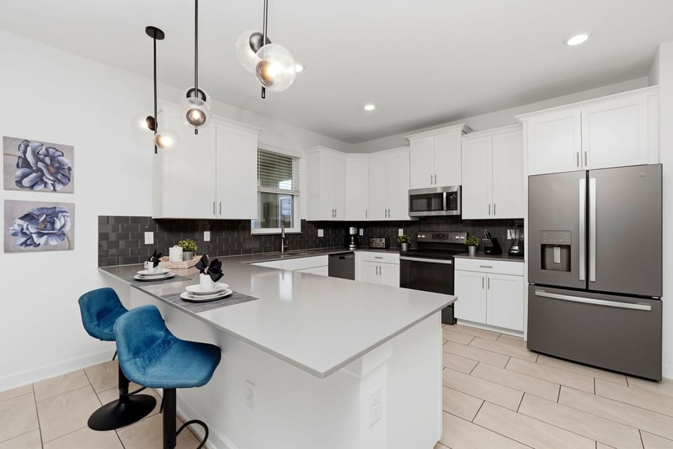Modern kitchen with white cabinetry and a breakfast bar with blue stools
