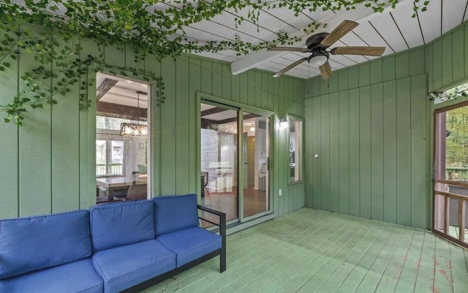 The enclosed porch offers a sheltered sofa and forest views.