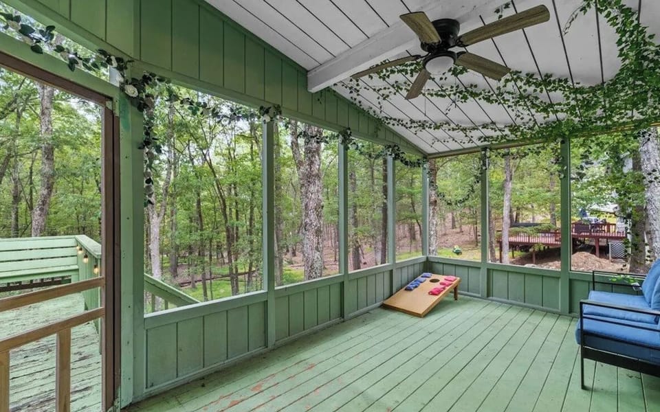 The enclosed porch also provides a cornhole game area with panoramic wooded views.