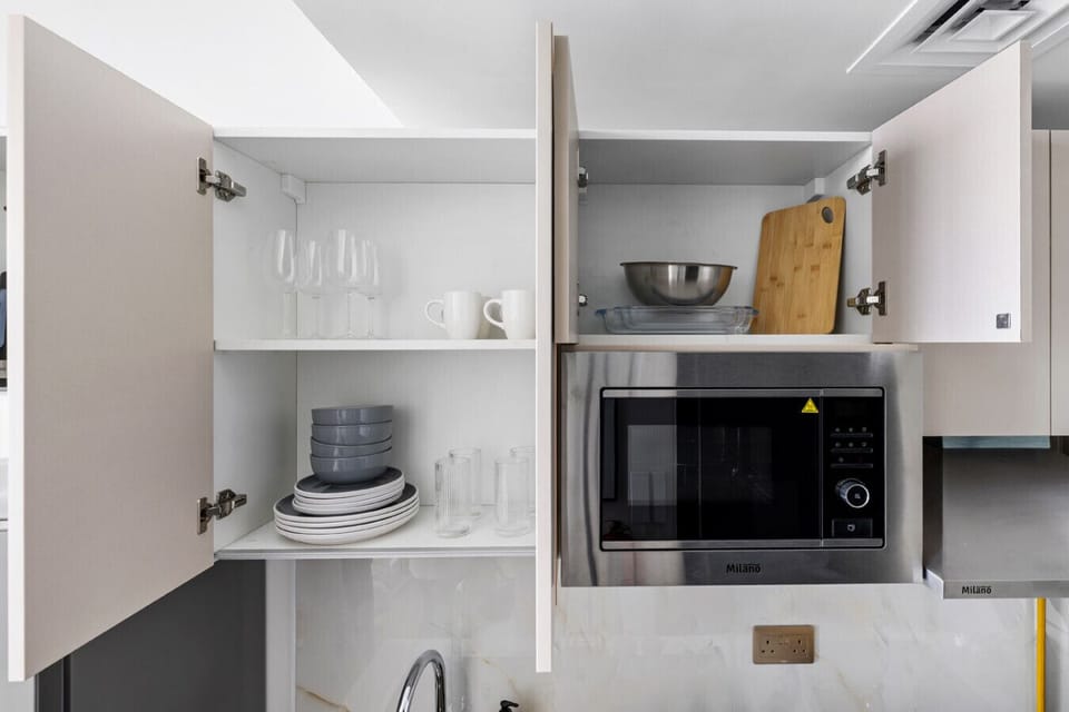 Organized shelves with plates, mugs, glasses, and essentials above the cooker