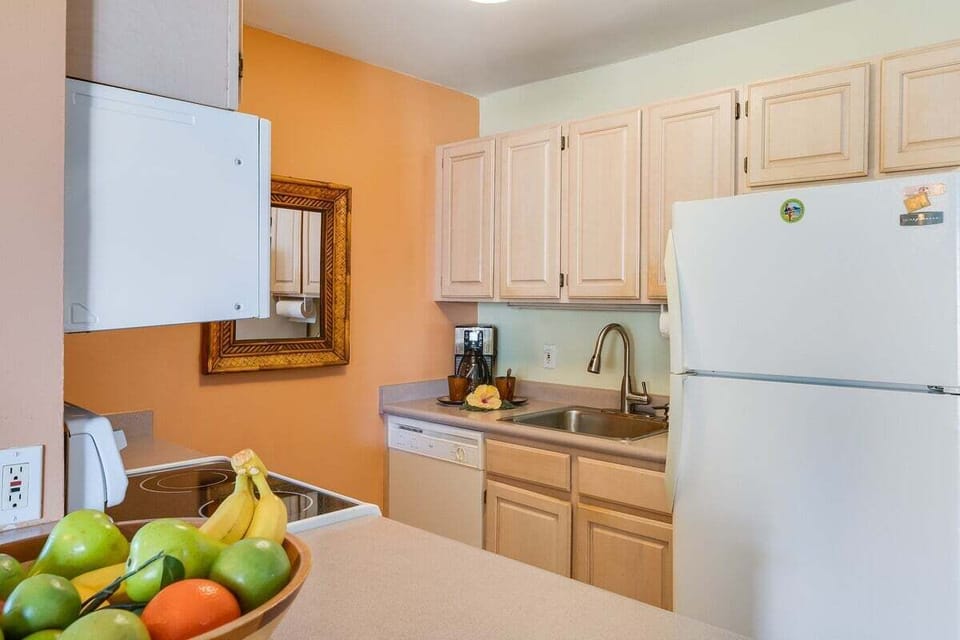 A clean, functional kitchen with light cabinetry, abundant counter space, and a fresh bowl of fruit for a welcoming touch.