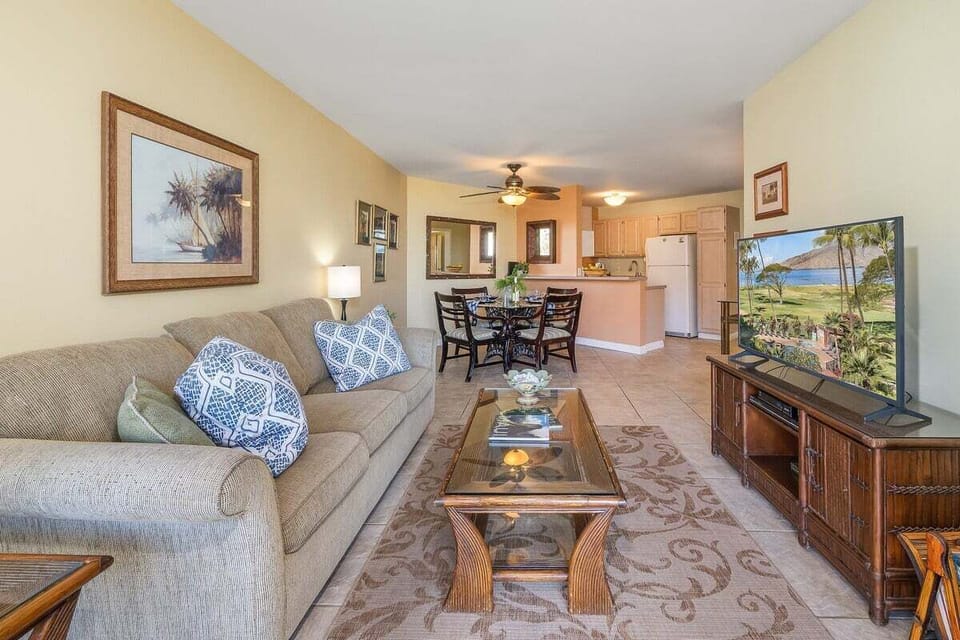 A spacious living room with warm lighting, tropical décor, and a seamless flow toward the dining area.