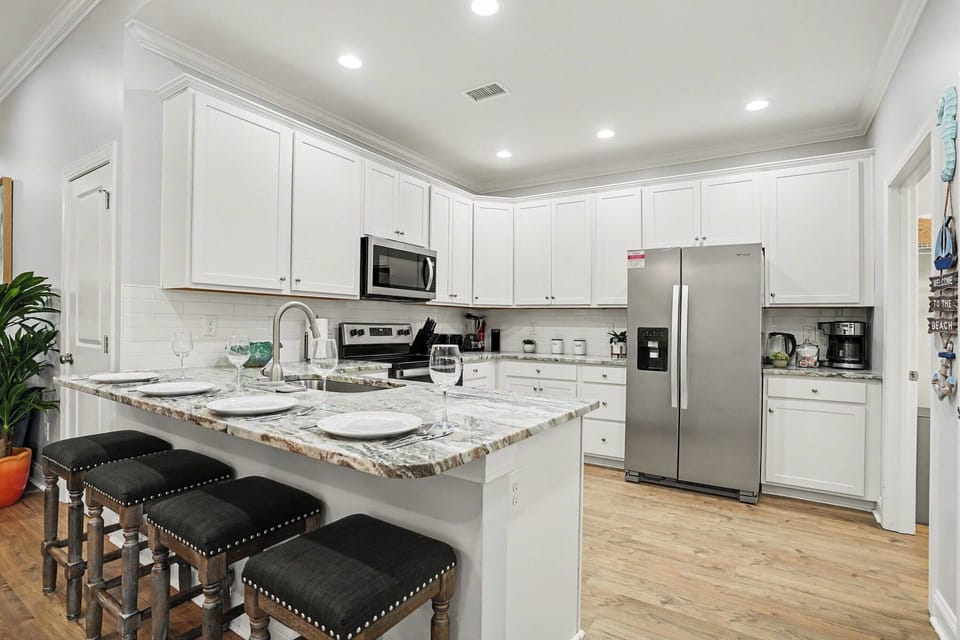 Prepare and gather in style at Sea Princess—crisp white kitchen featuring a large island, stainless fridge, and coastal charm.