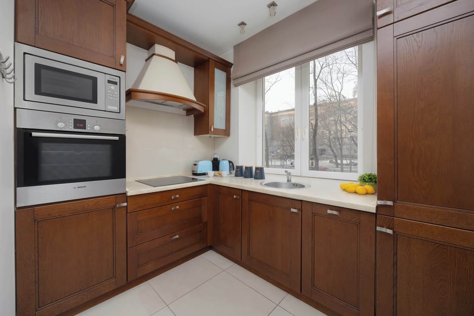 Compact modern kitchen with wooden cabinets and built-in appliances.