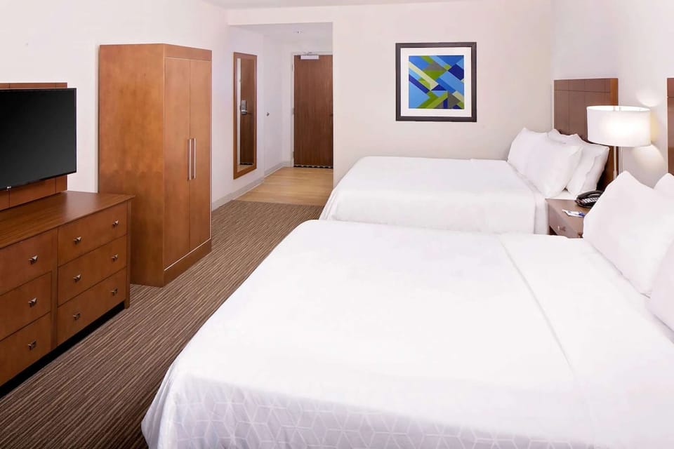 Two-bed guest room with TV, wardrobe, and warm wood finishes