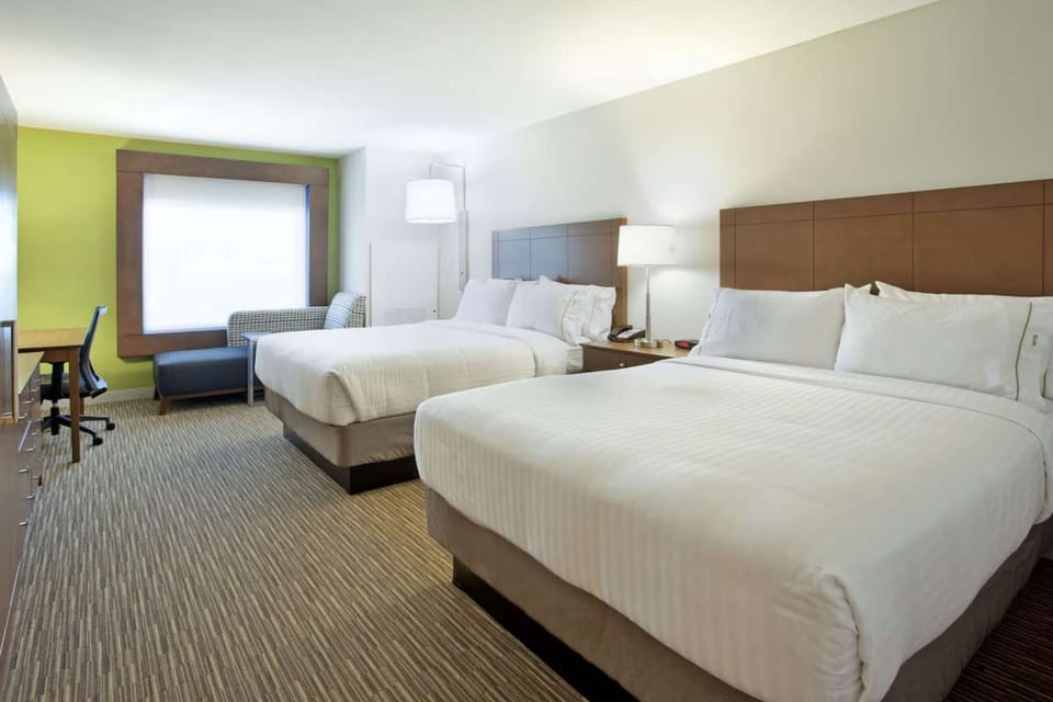 Spacious room with two beds, desk, and soft green accent wall