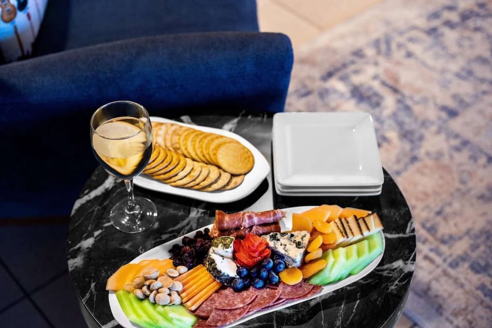 Wine, crackers, and a cheese board served on a black table
