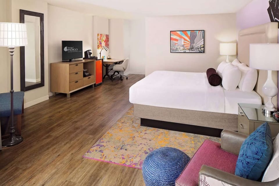 Large room with king bed, TV, bright wall art, and work desk