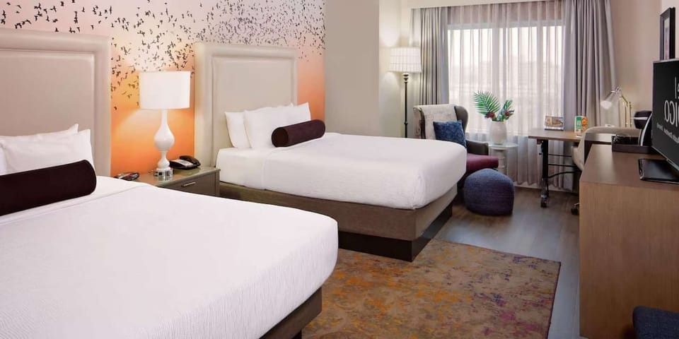 Two queen beds with sunset bird mural and cozy work desk area