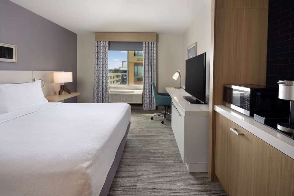 Bright king room with TV, desk, microwave, and coffee maker