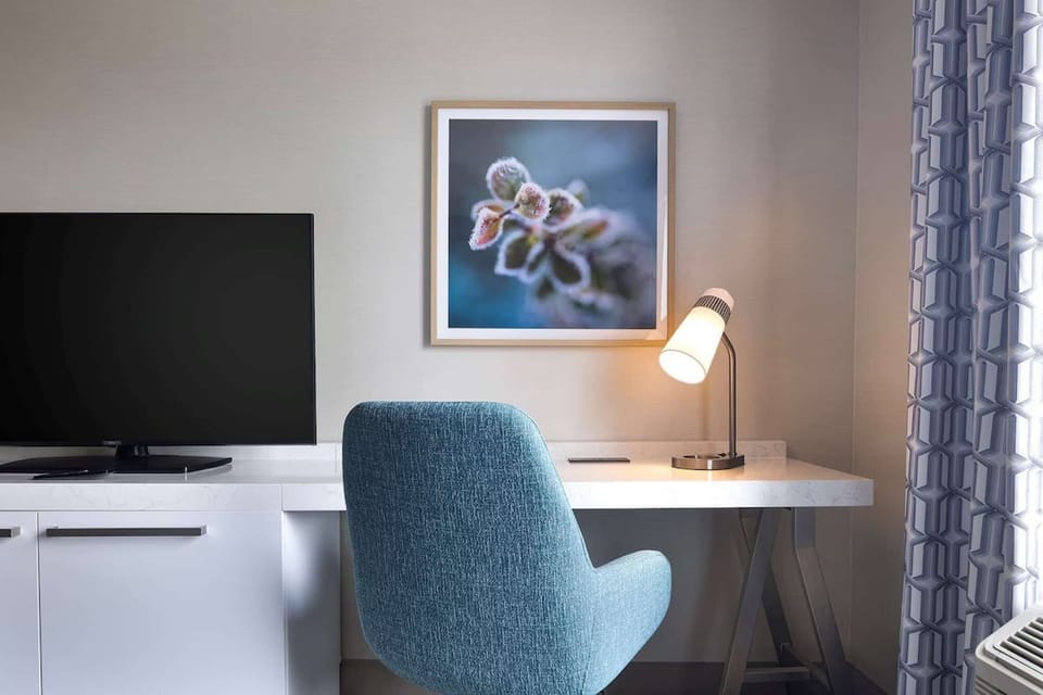 Work desk with lamp, TV, and blue chair beside the window