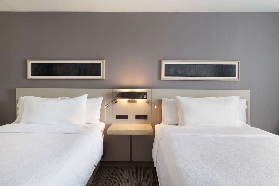 Cozy setup with two double beds, bedside lamps, and simple wall art