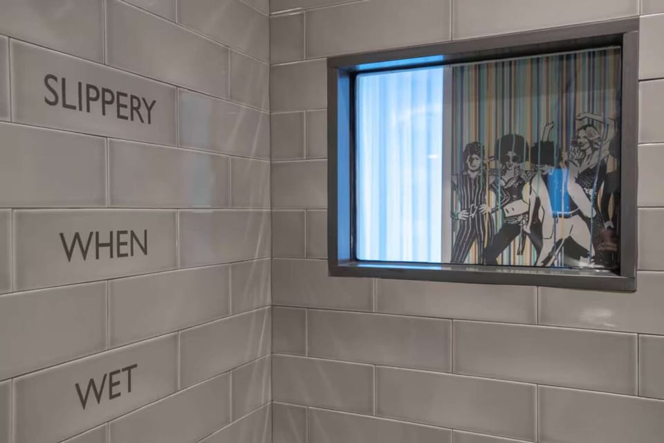 Shower wall with bold “Slippery When Wet” text and inset art