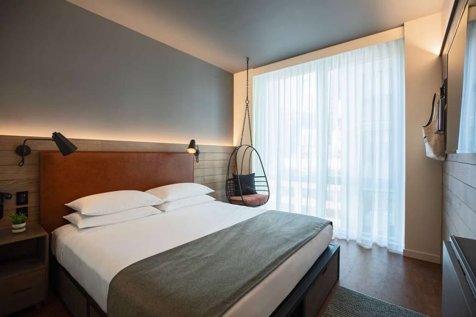 King guest room with leather headboard, wall lamps, hanging chair