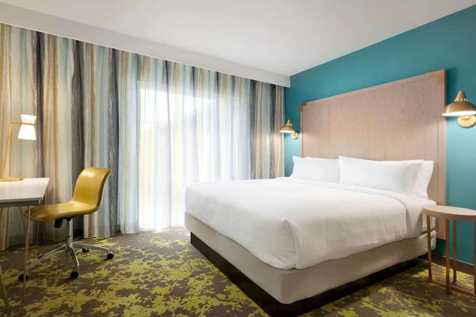 King bed with work desk and soft window light