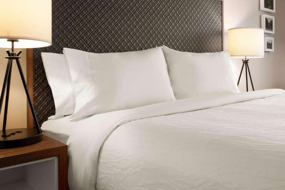 Bed with crisp white linens and warm lighting from side lamps.