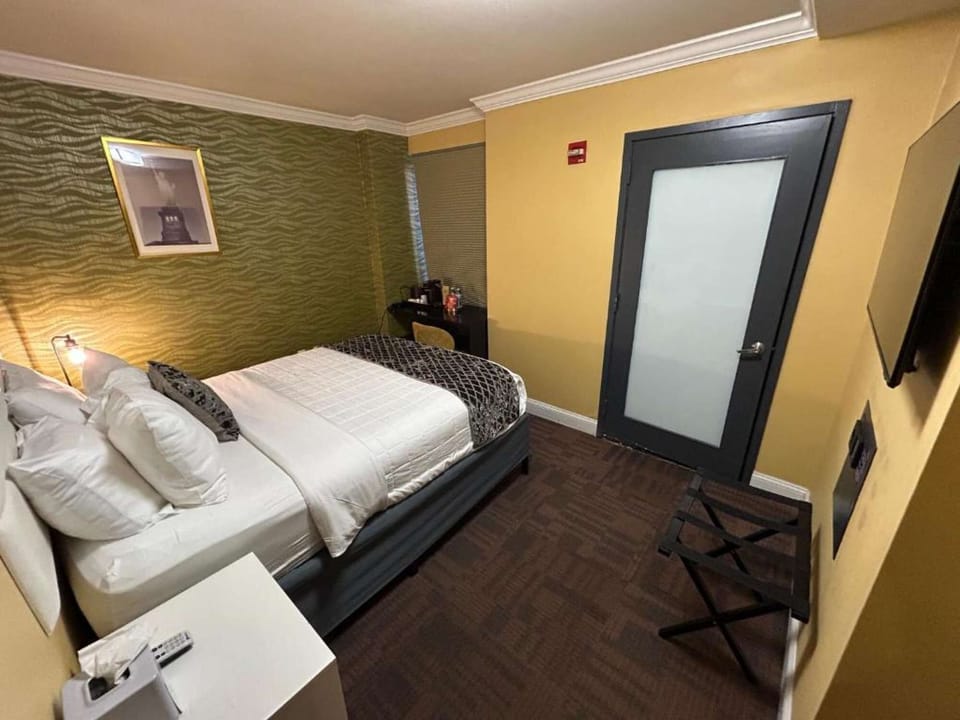 Room with patterned wall, neatly made bed, and work desk setup.