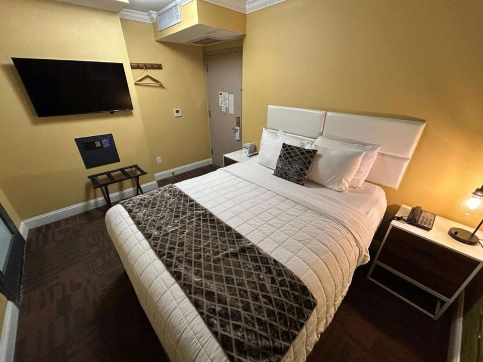 Room featuring wall-mounted TV, bedside tables, and neatly arranged bedding.