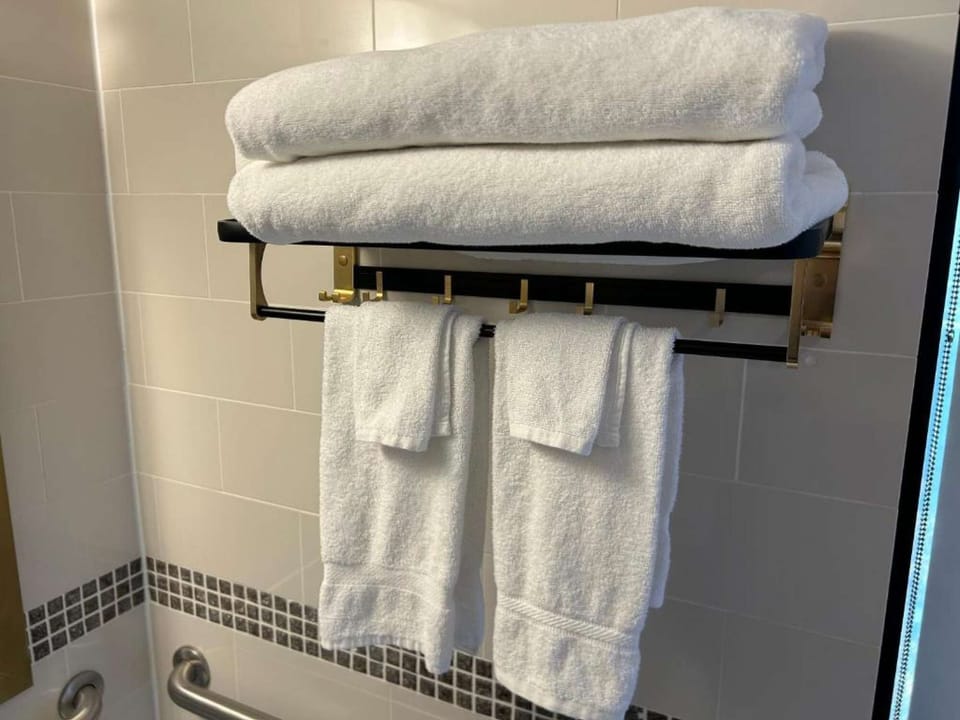 White towels stacked neatly on a gold-accented rack above rail.