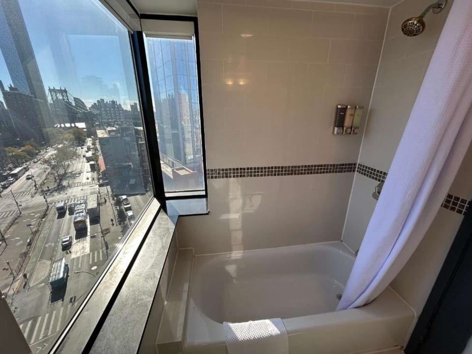 Corner window bath view overlooking busy city streets and towers.