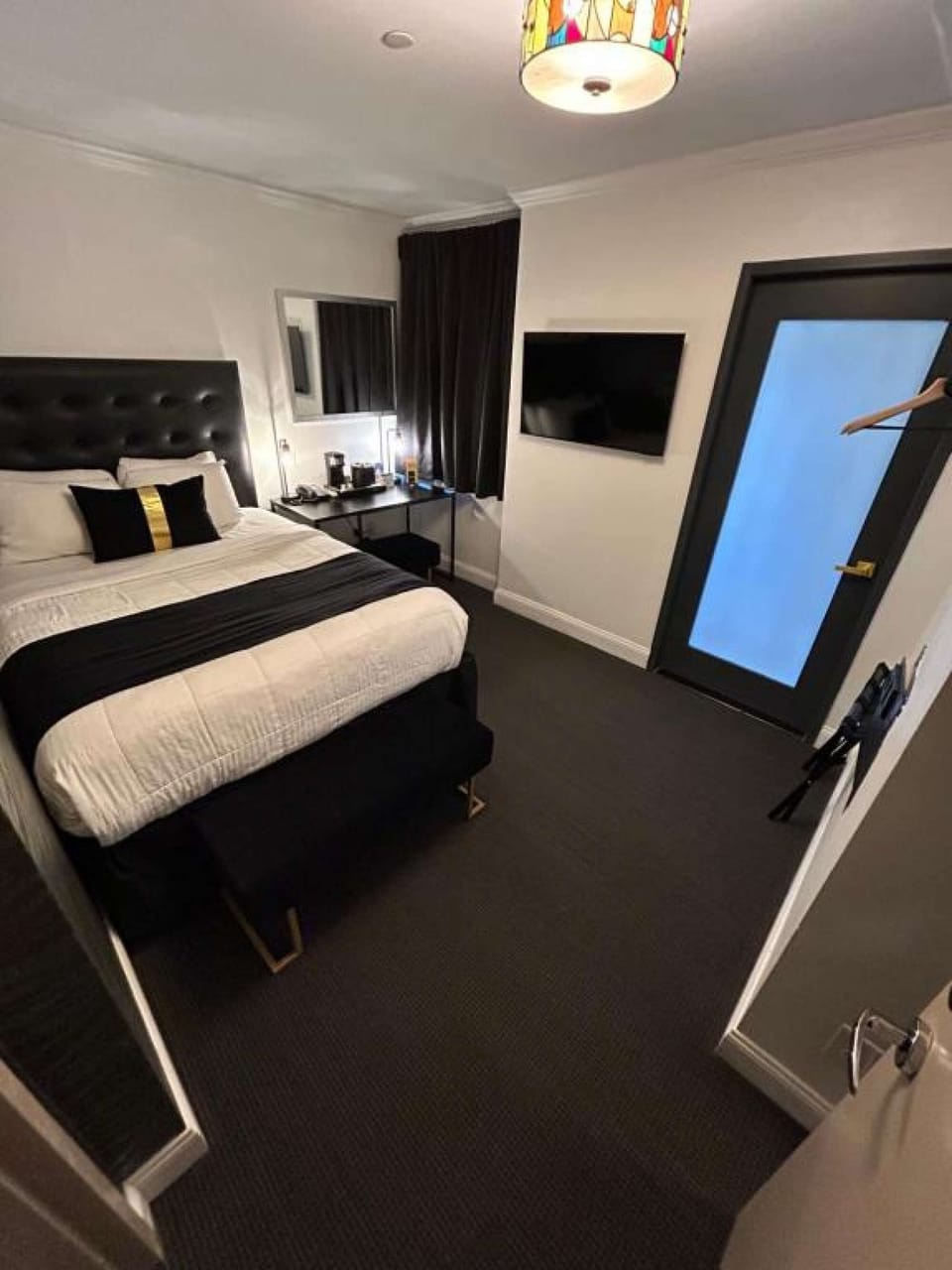 Room corner with wall mirror, hanger rack, and entry door.